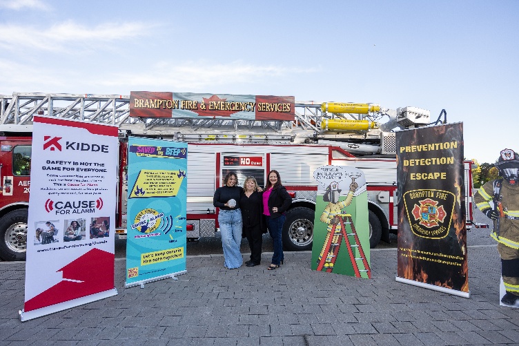 An image of three people in front of a fire truck and surrounded by promotional posters.