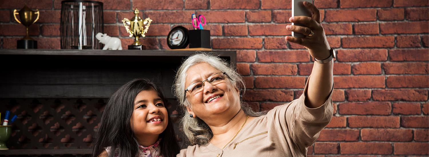 Page Banner - A senior and her grandchild looking at a mobile phone