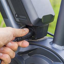 Image of a person's hand plugging in a charging adapter into a e-bike